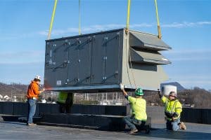 A crane lowering a commercial HVAC unit onto the roof of Rocktown High School and being set up by Riddleberger Brothers, Inc. employees