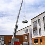 drone shot of a crane lifting a commercial HVAC unit onto the roof of Rocktown High School by Riddleberger Brothers, Inc.