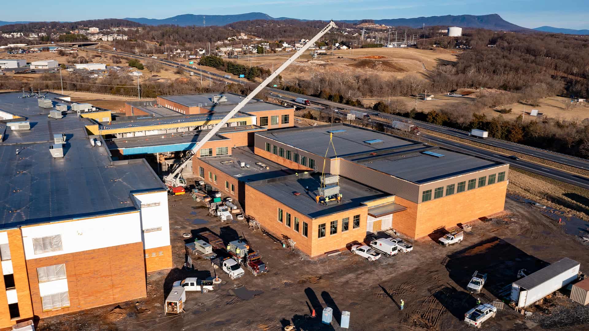 drone shot of a crane lowering a commercial HVAC unit onto the roof of Rocktown High School by Riddleberger Brothers, Inc.