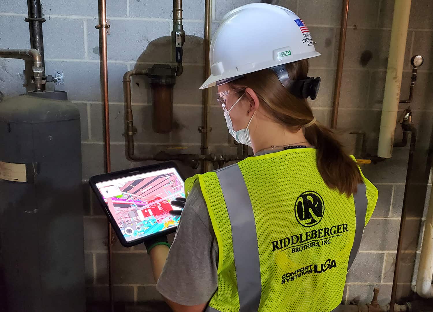 An RBI technician reviewing a visual intelligence image on a tablet while inspecting equipment.