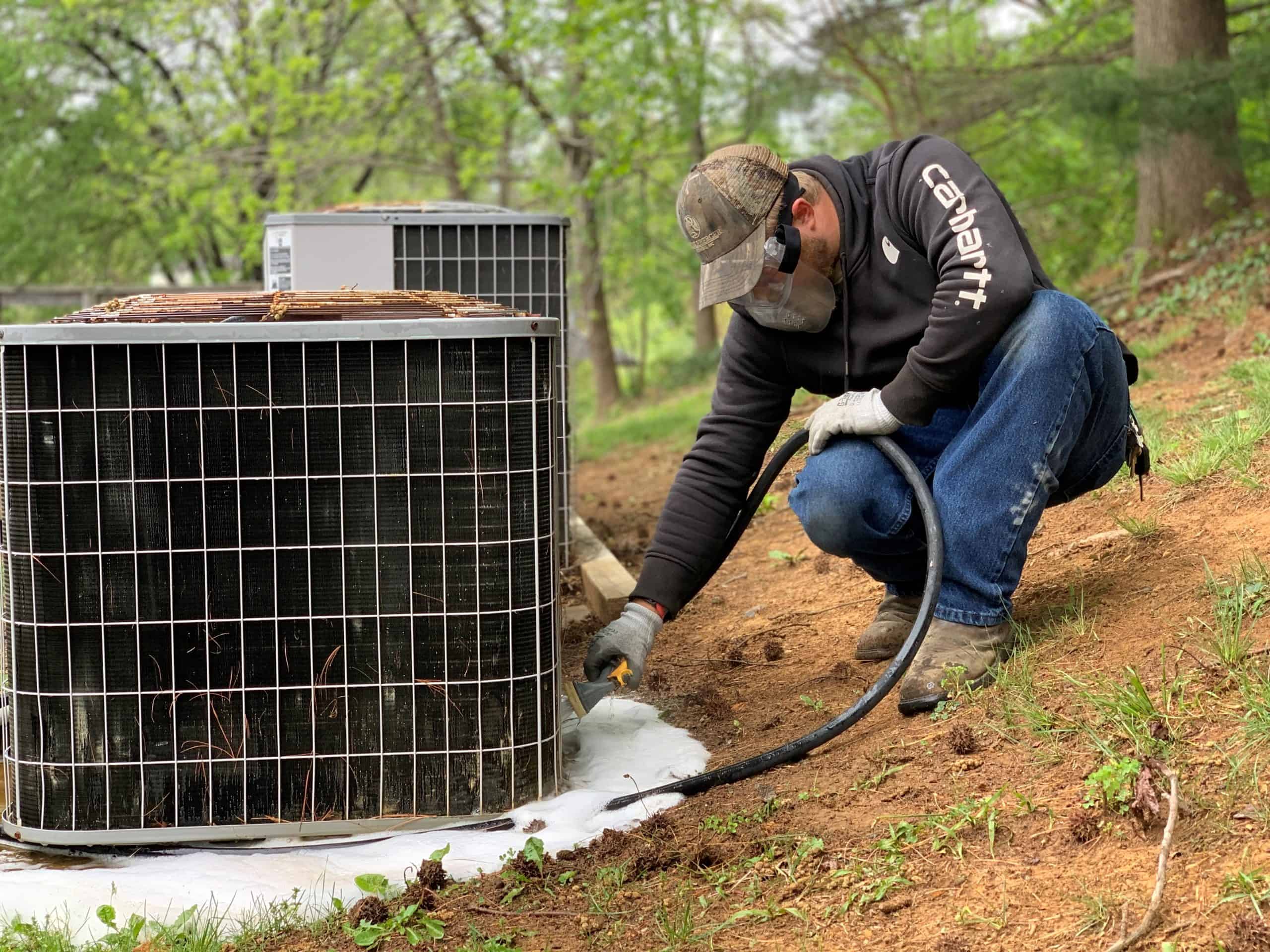 RBI employee cleaning debris from outside HVAC units