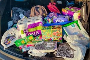 Paper towels, tissues, composition books, and other donate school supplies in the back of a car
