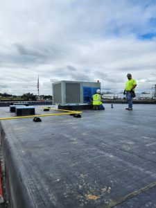 Employees installing an HVAC unit on the roof of RBI's new expansion building.