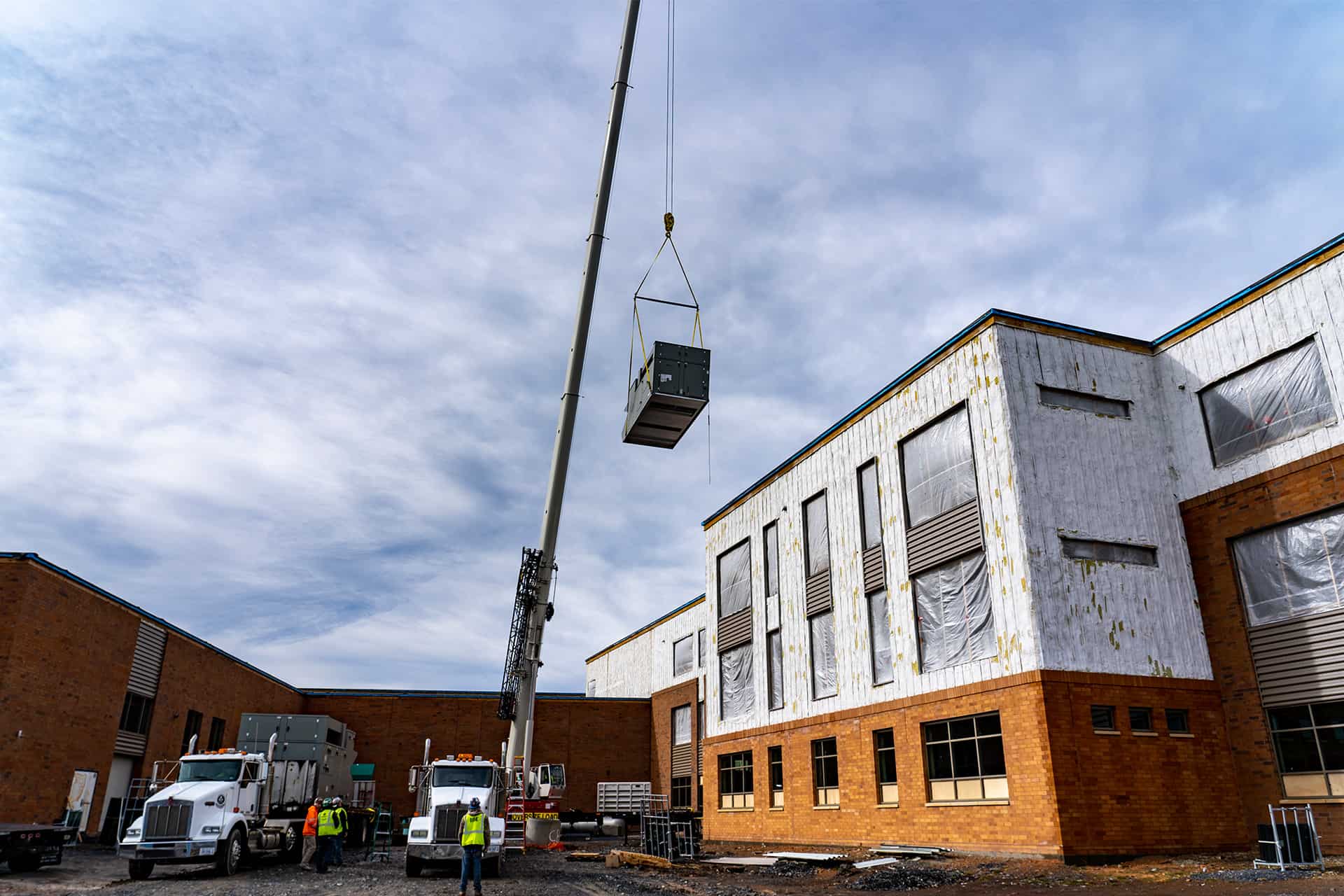 RBI's construction team on-site at Rocktown High, using a crane to place an HVAC unit on the roof.