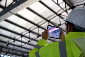 A construction worker using a tablet to see the structure of a building with BIM software.