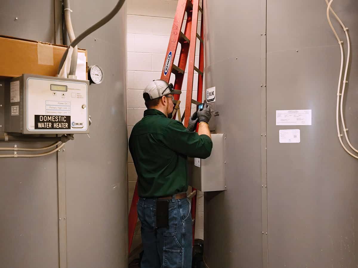 A plumbing technician performing service on a commercial hot water heater.