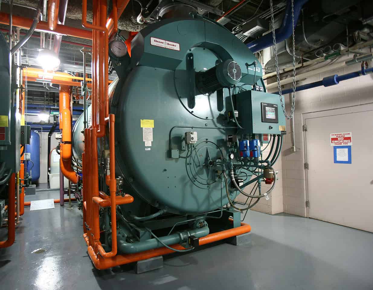 A large commercial boiler system in the boiler room of a facility.