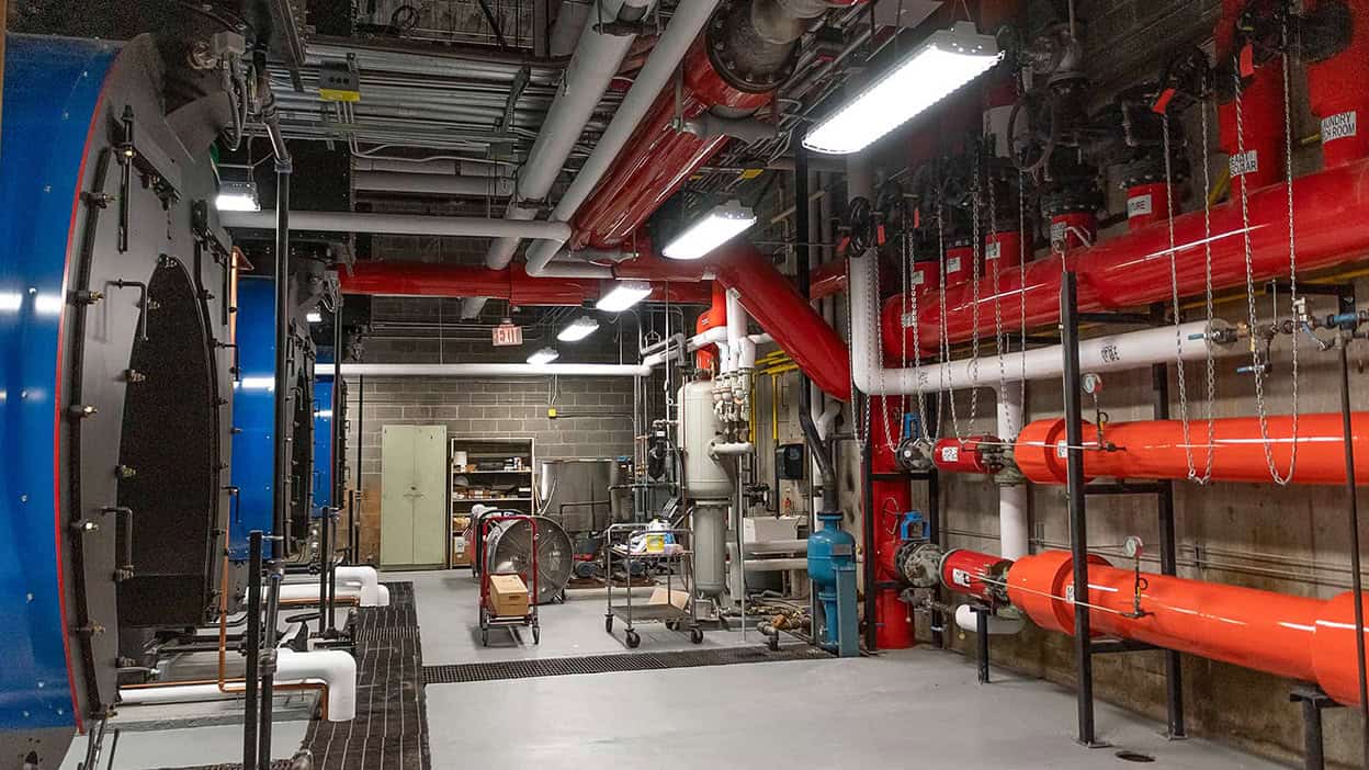 A facility's boiler room containing large red pipes and commercial boilers.