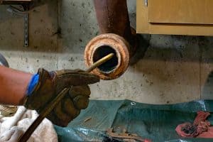 A plumbing technician cleaning out a drain.