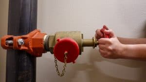 Hands turning a water emergency shutoff valve