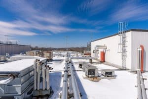 The rooftop of a commercial building with snow on it in front of a clear blue sky