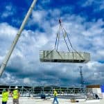 RBI employees lowering an HVAC system onto a rooftop with a crane