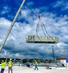 RBI employees lowering an HVAC system onto a rooftop with a crane