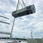 RBI employees lowering an HVAC system onto a rooftop with a crane