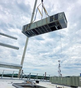 RBI employees lowering an HVAC system onto a rooftop with a crane