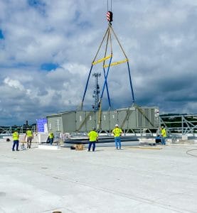 RBI employees lowering an HVAC system onto a rooftop with a crane