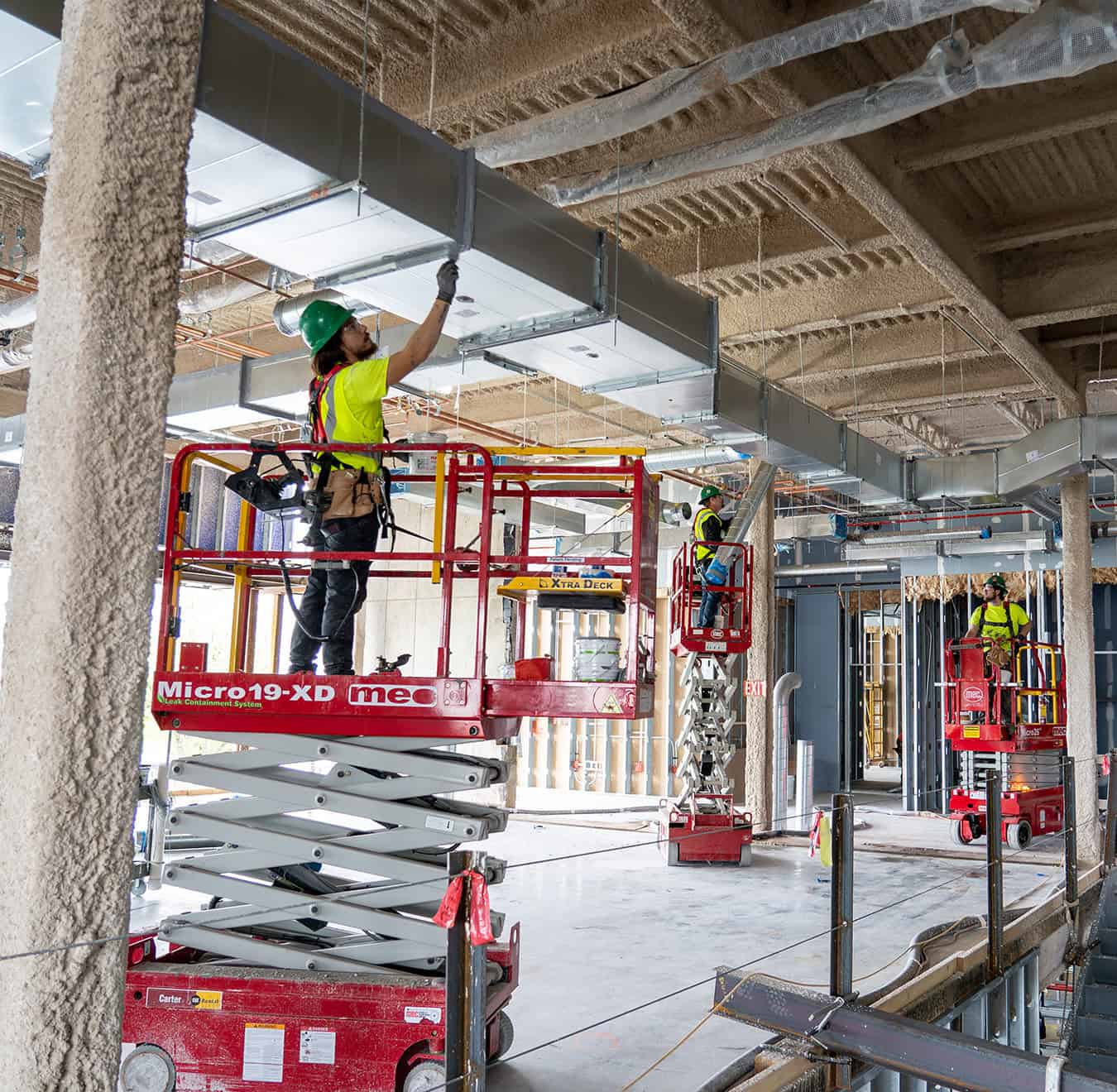 RBI-Summer-Building-Maintenance-Structural-Maintenance RBI employees on scissor lifts installing ductwork in a new build.