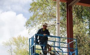 An RBI employee on a lift in front of trees.