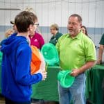 RBI employee handing a green hard hat to a student