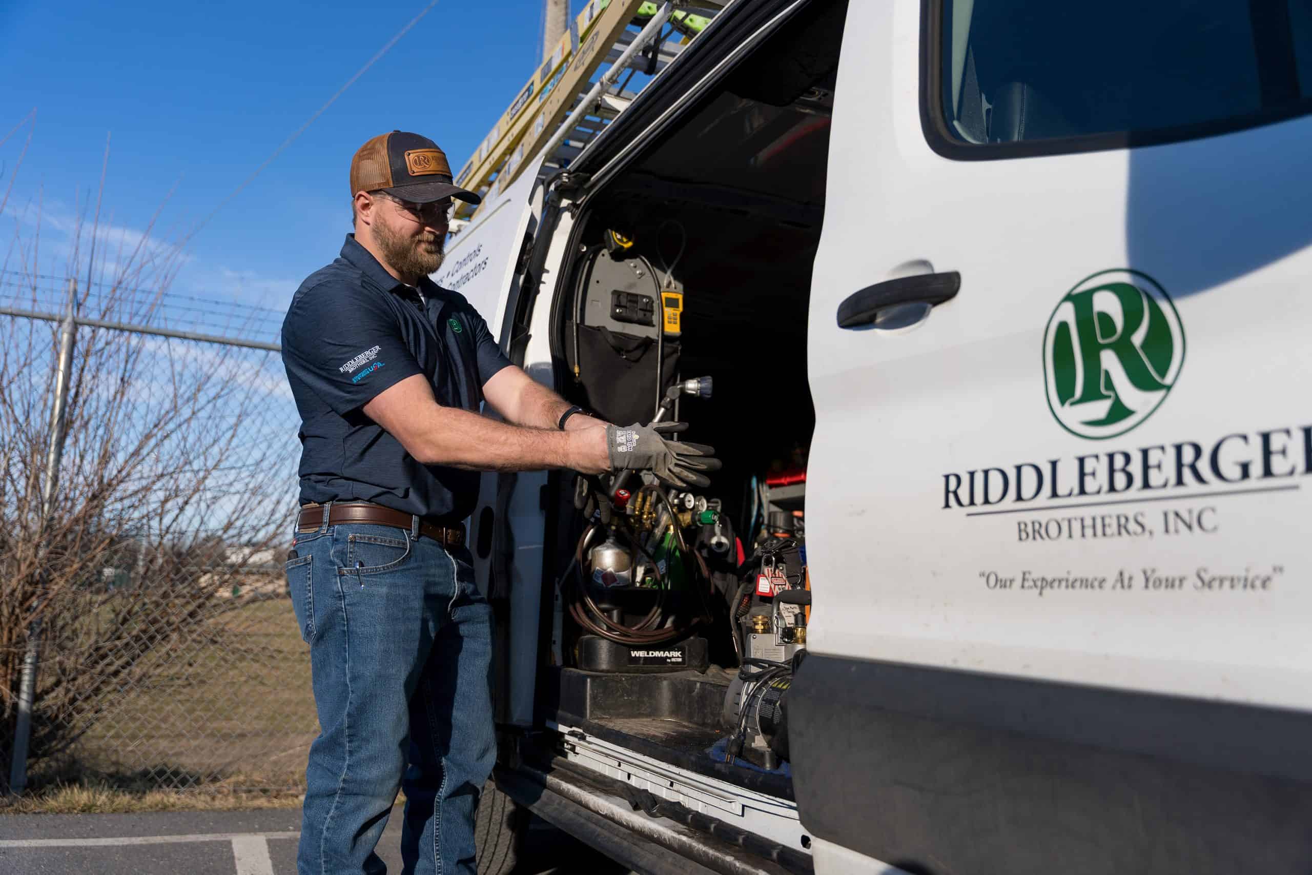 An RBI employee putting on gloves next to an open RBI service van