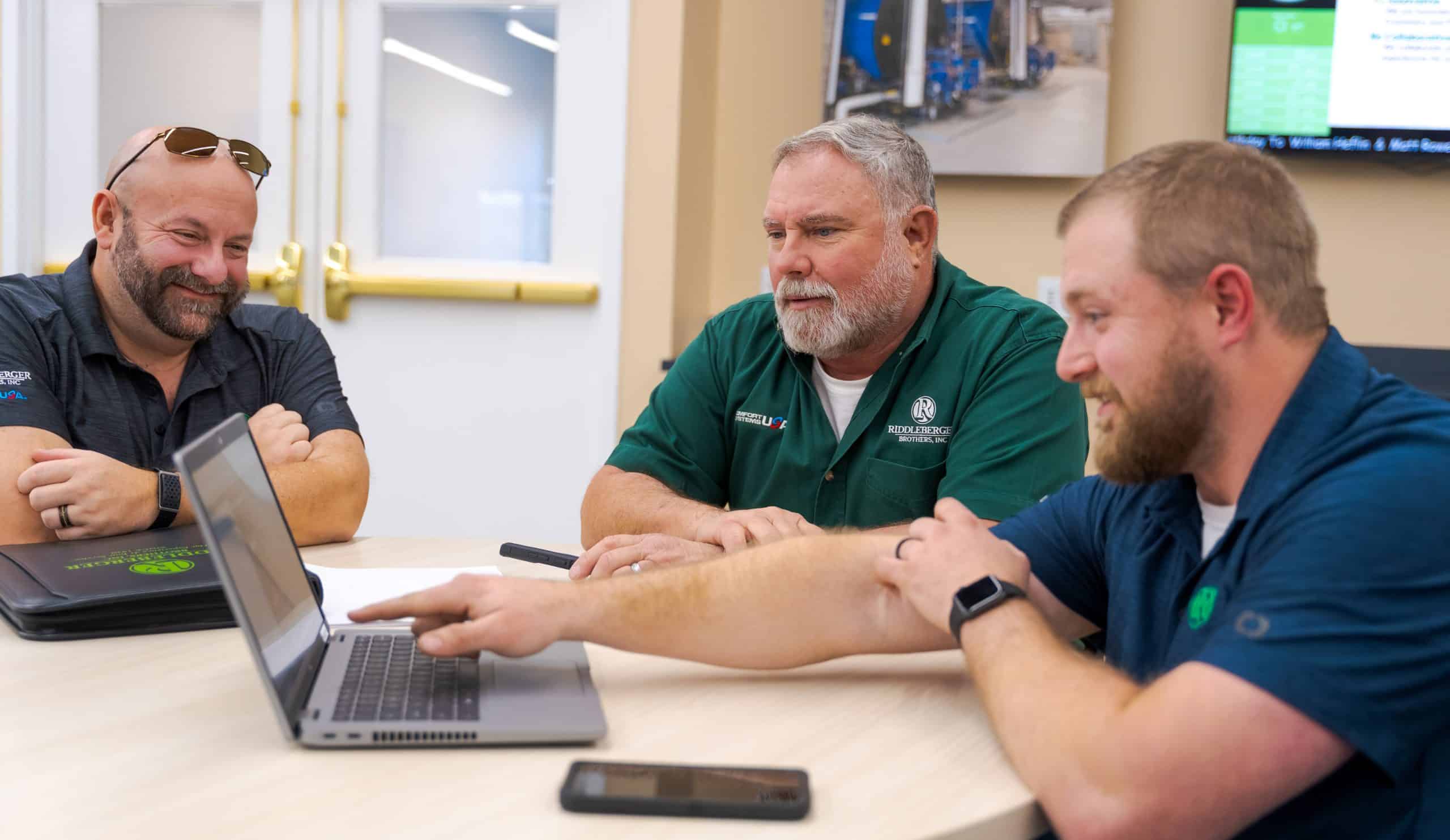 RBI service team members at a table viewing data on a laptop