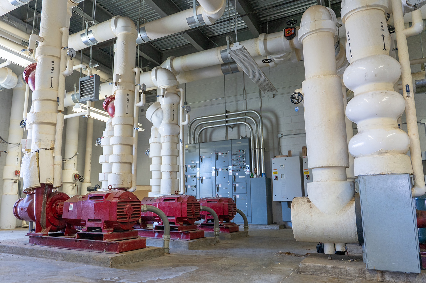 Facility room with centrifugal pumps, insulated thermal piping, and electrical control panels